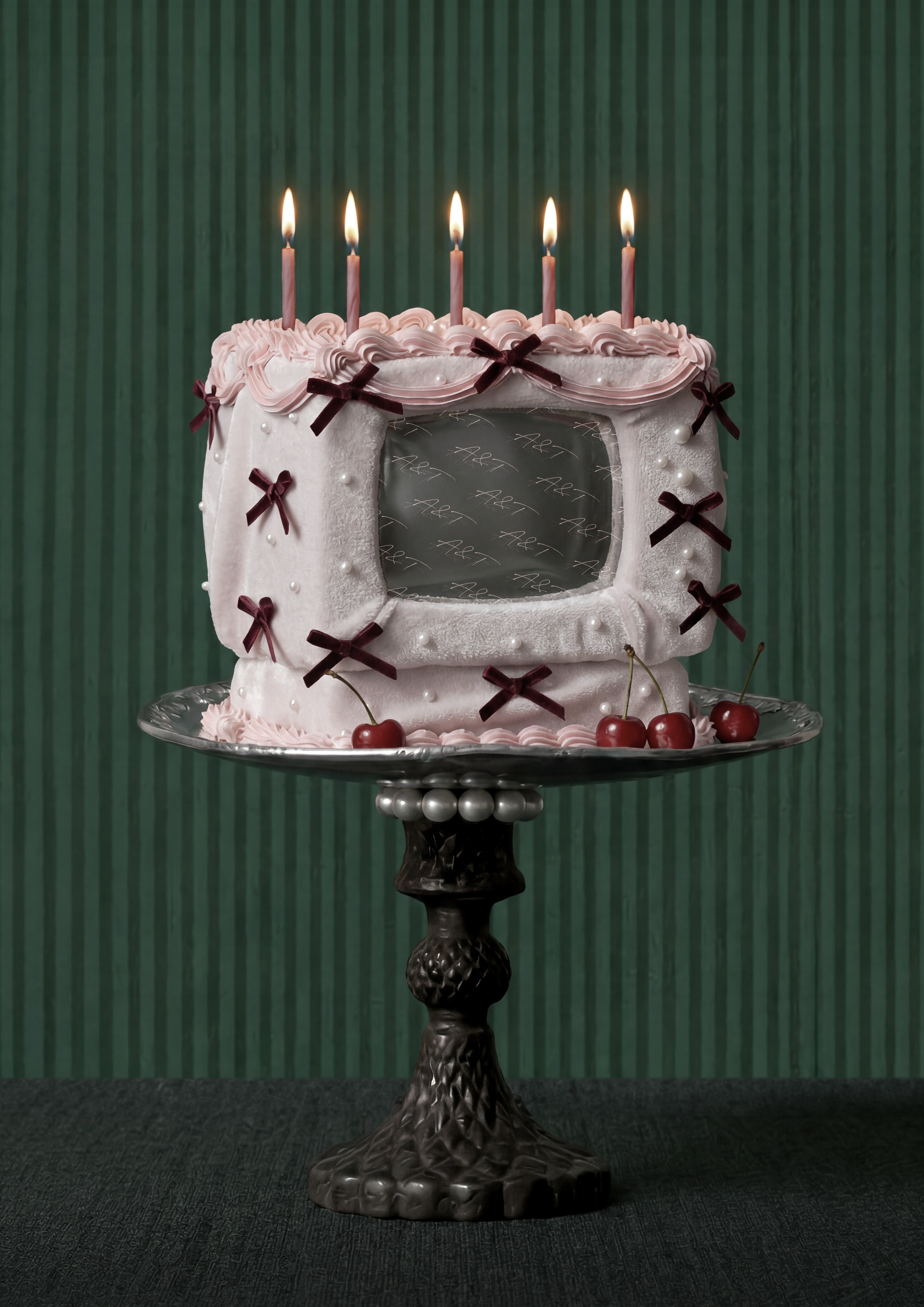Pink cake on a silver stand against a deep green background